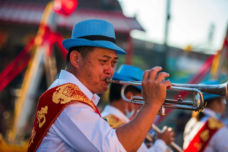 man playing the trombone while in blue band uniform