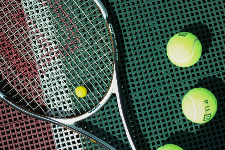 a close up of a racket, ball and tennis balls on the ground