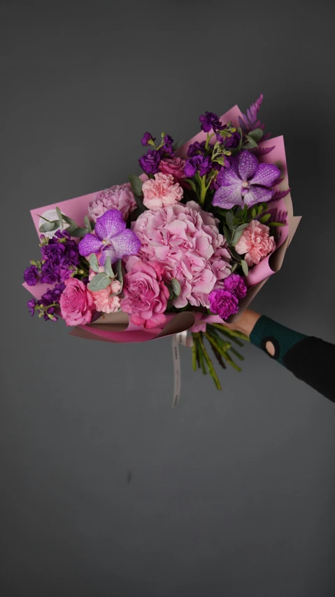 someone's hand holding up a bouquet of flowers