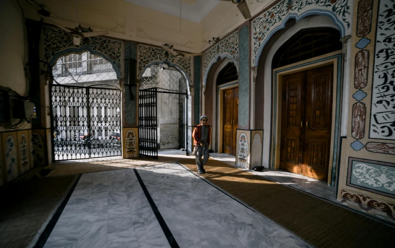 a person walking in an old hallway near large doors