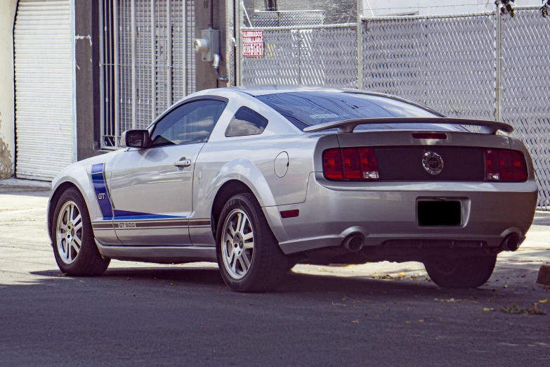 a silver mustang parked on the side of the street