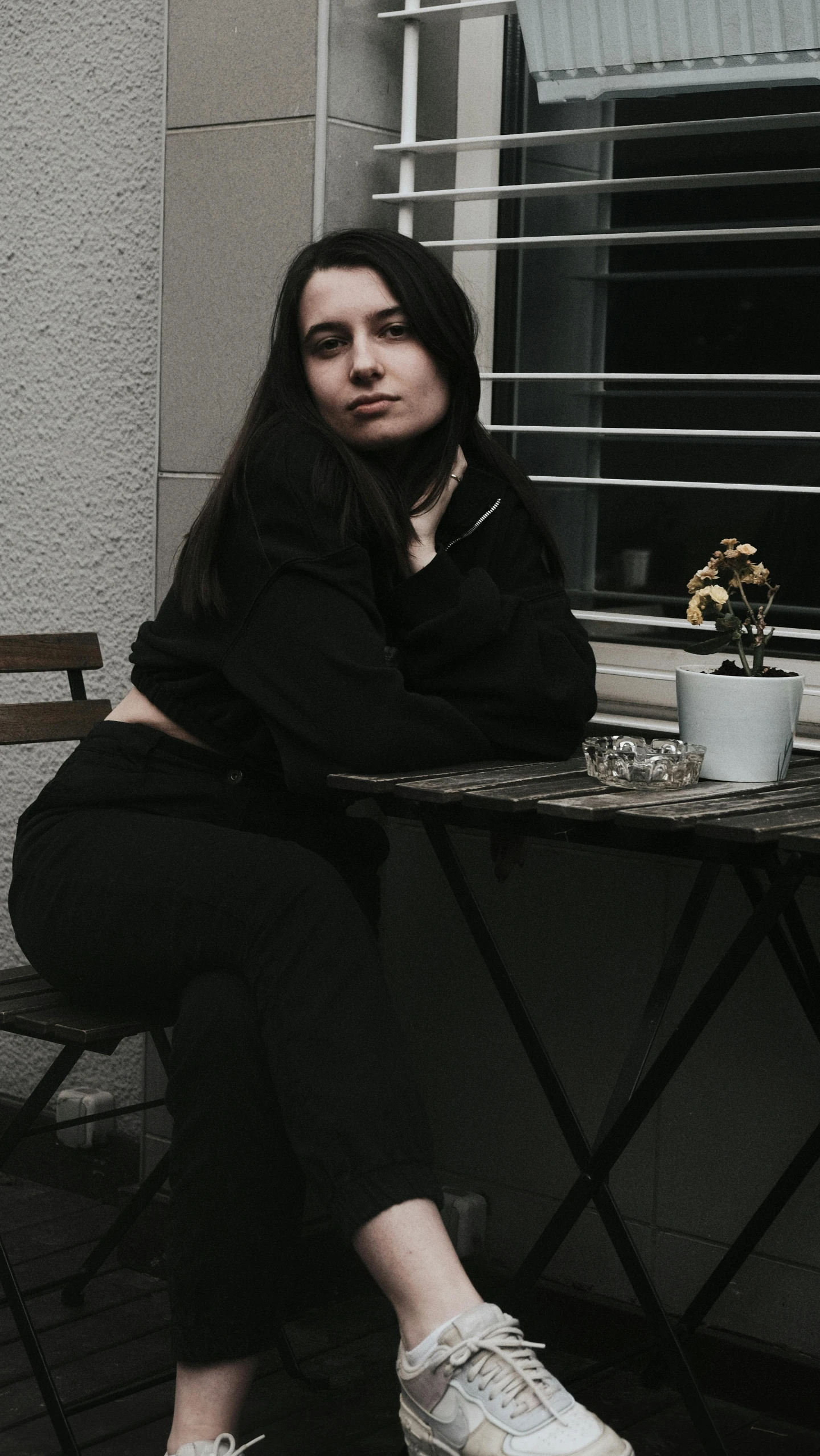 woman sitting on patio table with small potted plant