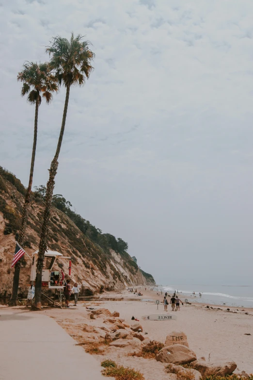 people standing around a beach next to a cliff