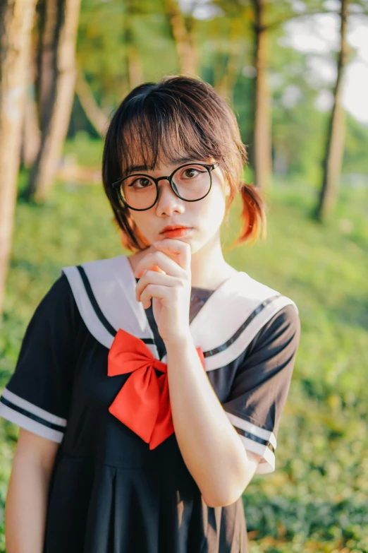 a woman wearing glasses stands in front of a row of trees