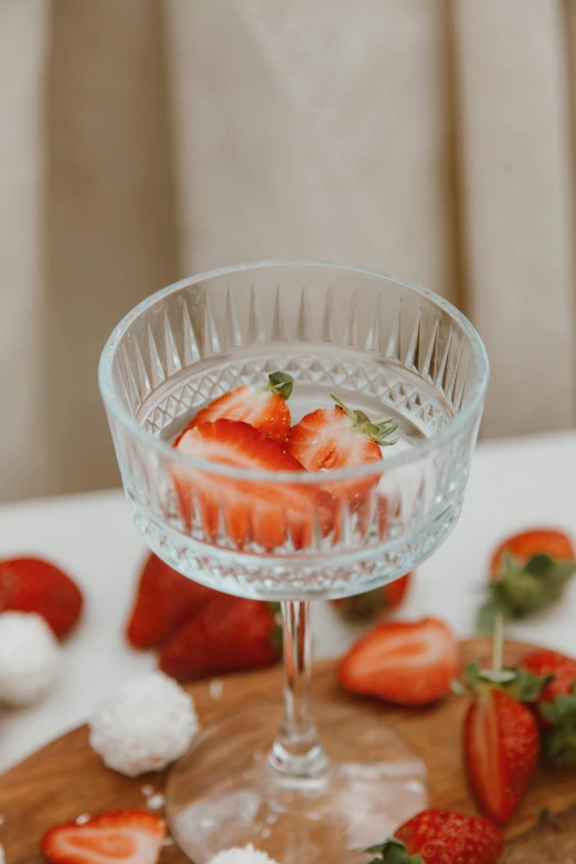 a clear glass full of white cheese and strawberries