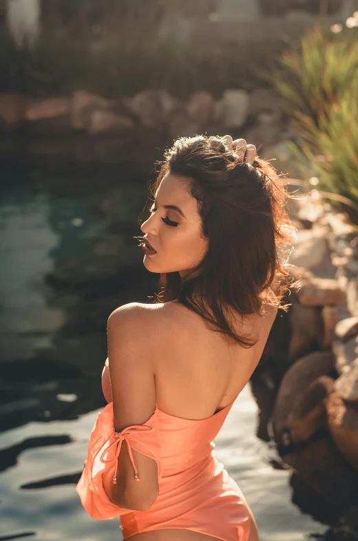the woman in an orange dress stands on a rocky beach