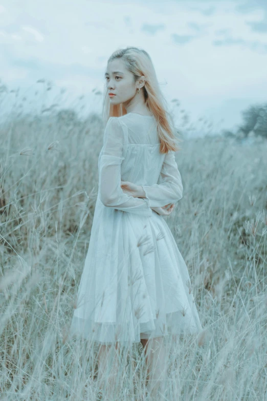 the woman standing in a field is wearing a white dress