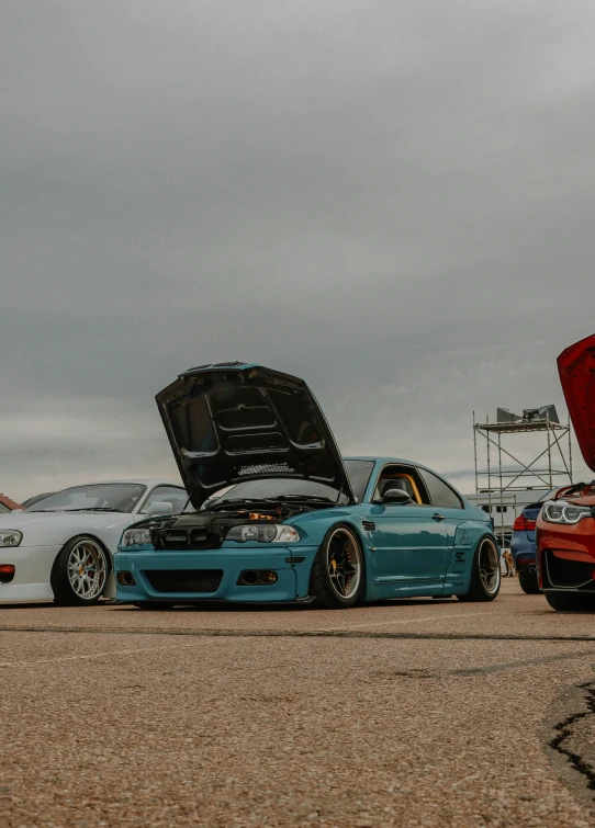 two cars with their hood open and the engine in the back ground