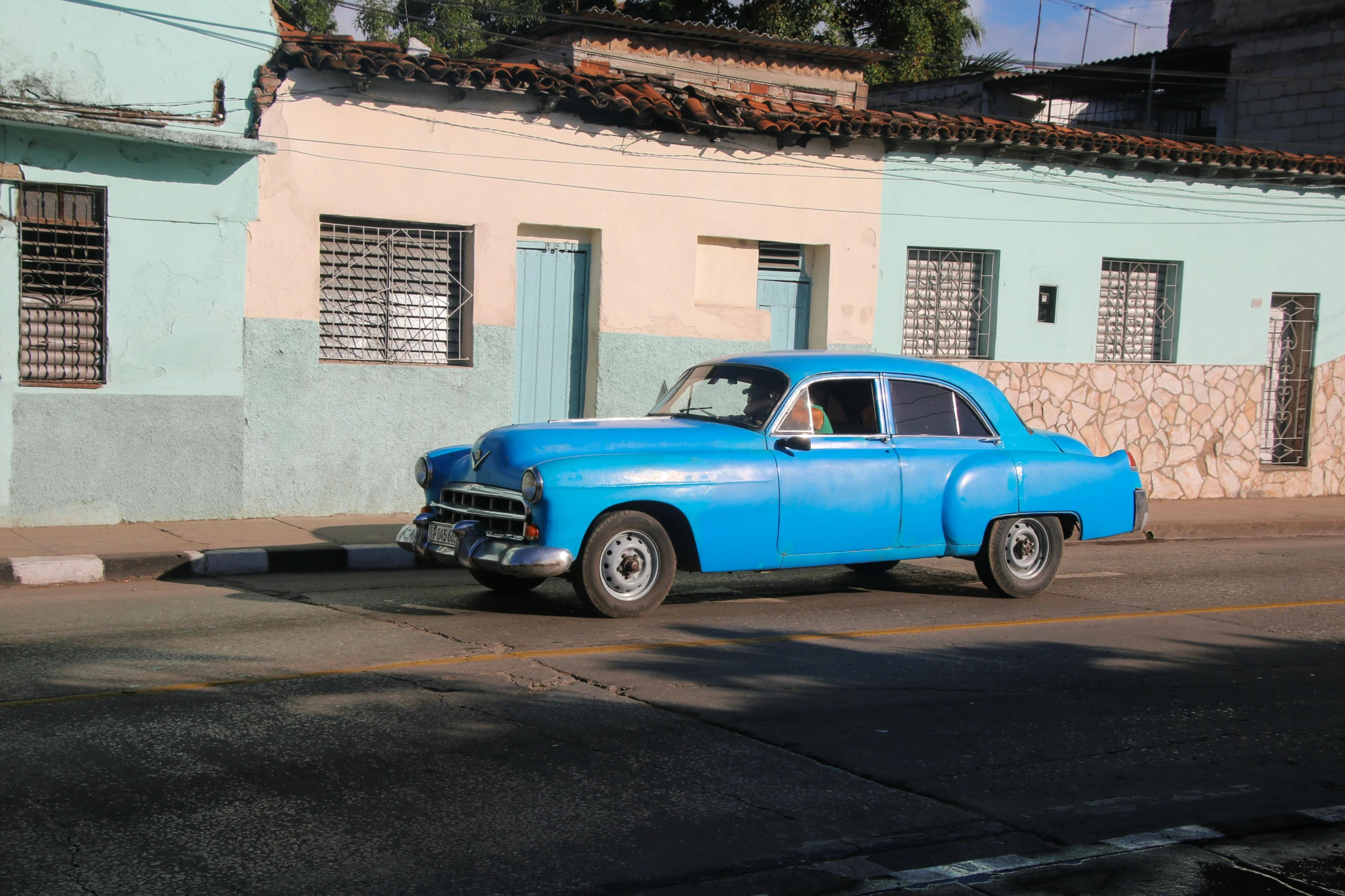 an old, blue car parked on the side of a road