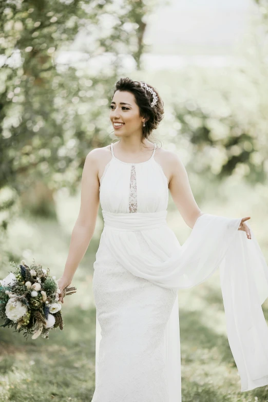 the bride with a white dress holds her bouquet