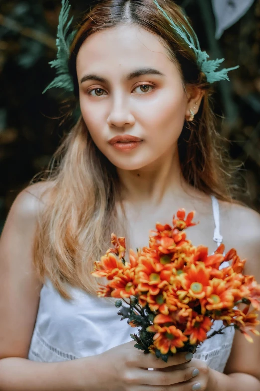 a beautiful young woman holding an orange bouquet