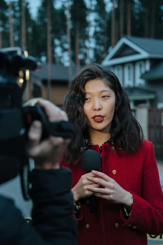 an asian woman speaking into microphone next to a man