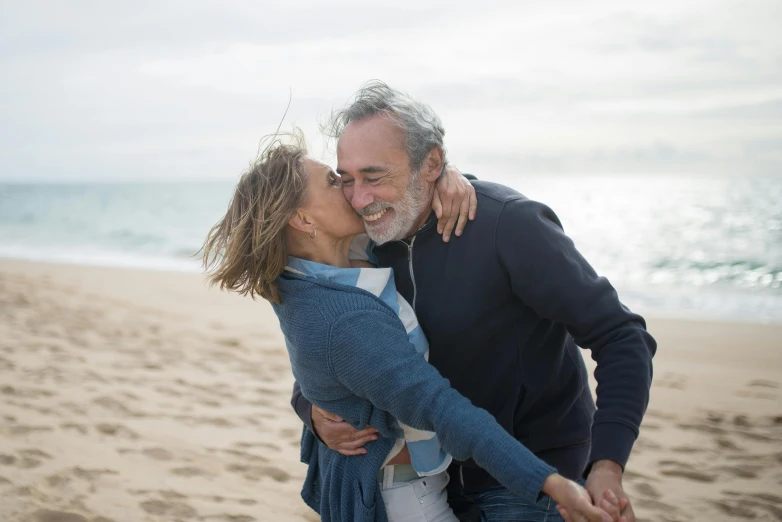 man and woman kissing on a sandy beach