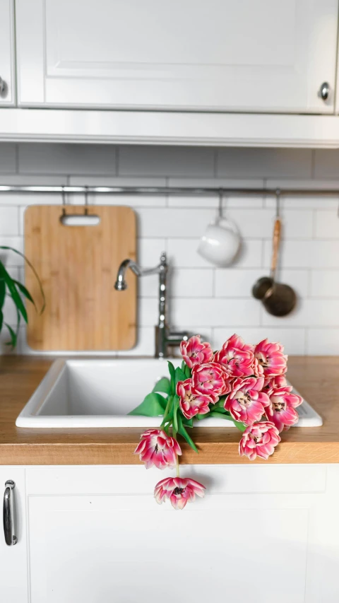 some pretty pink flowers sitting on the counter next to a sink