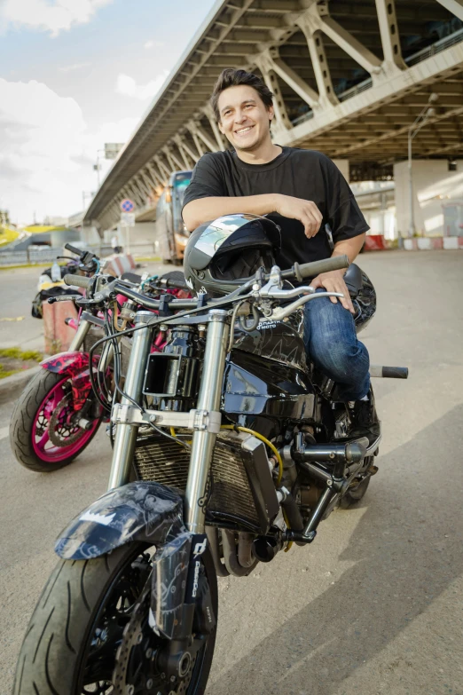 a man sitting on a black motorcycle smiling for the camera