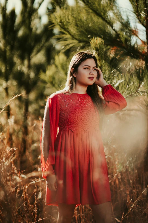 an asian girl standing in tall grass, talking on a phone