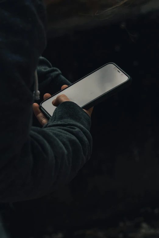 person holding cell phone displaying screen in dark environment