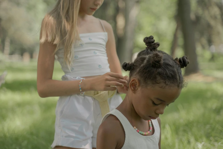 a little girl gets her hair done by an adult