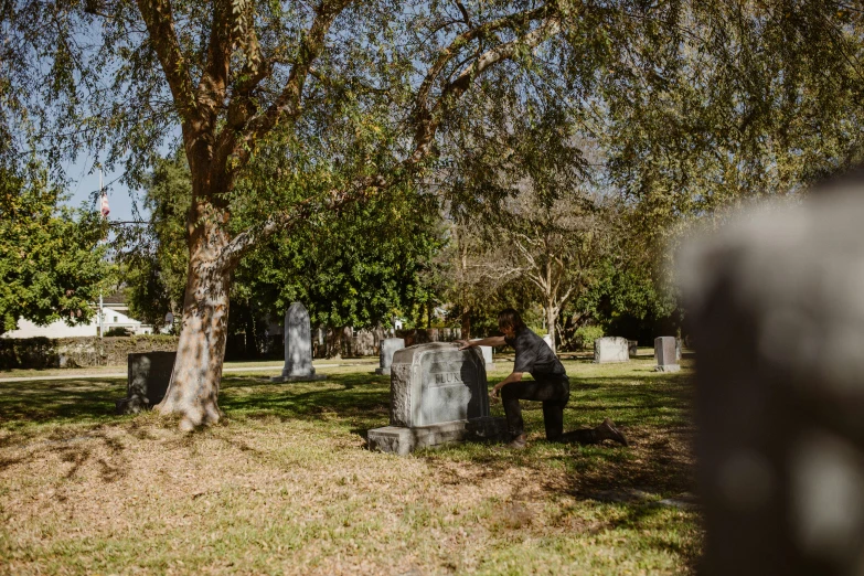 there are people standing at gravestones under the tree