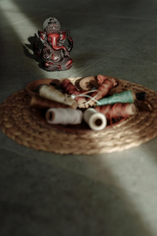 a small buddha statue sits beside an array of rolls of thread