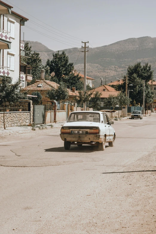 an old car sitting in a street between two houses