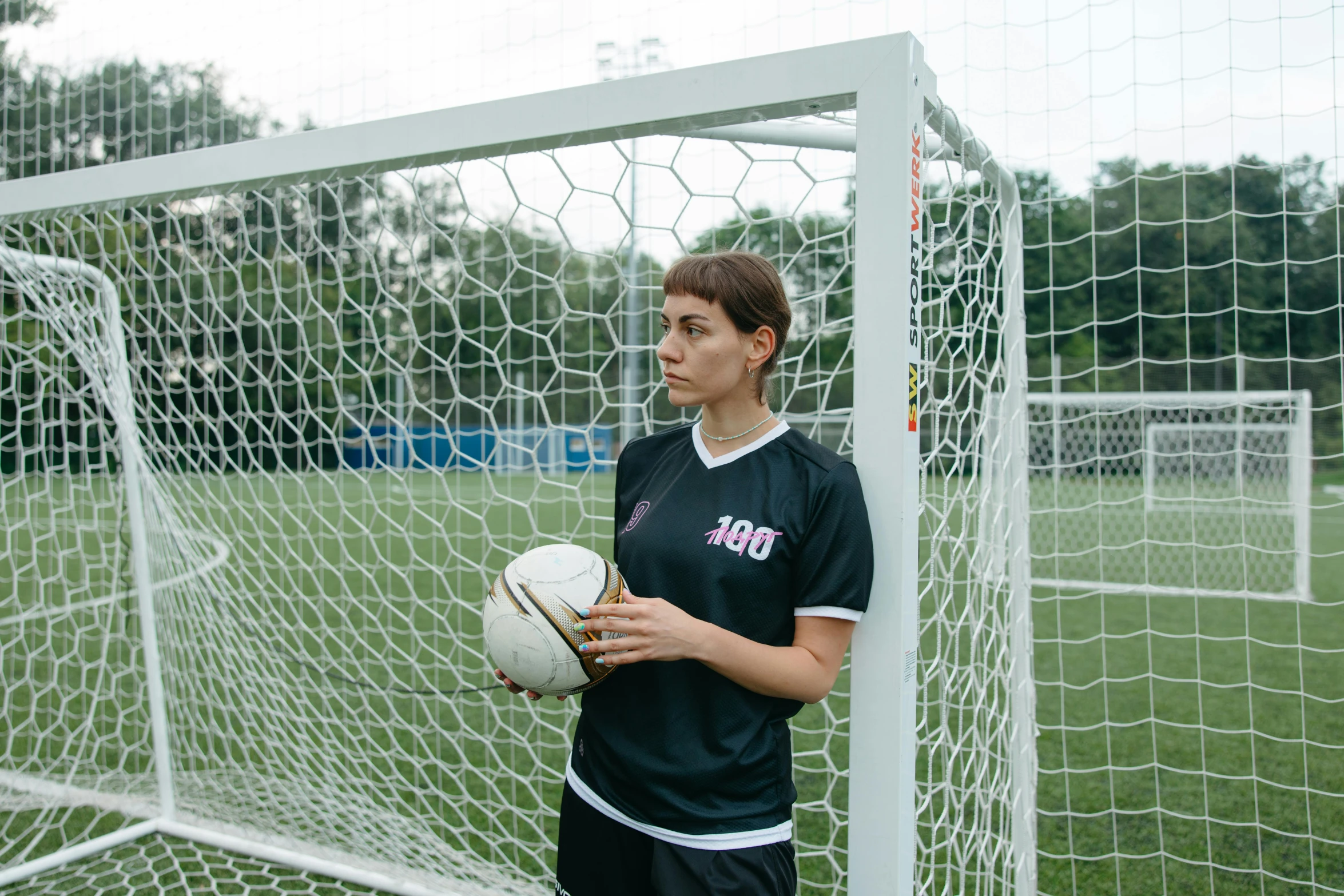 a soccer player stands in front of the goal holding a ball