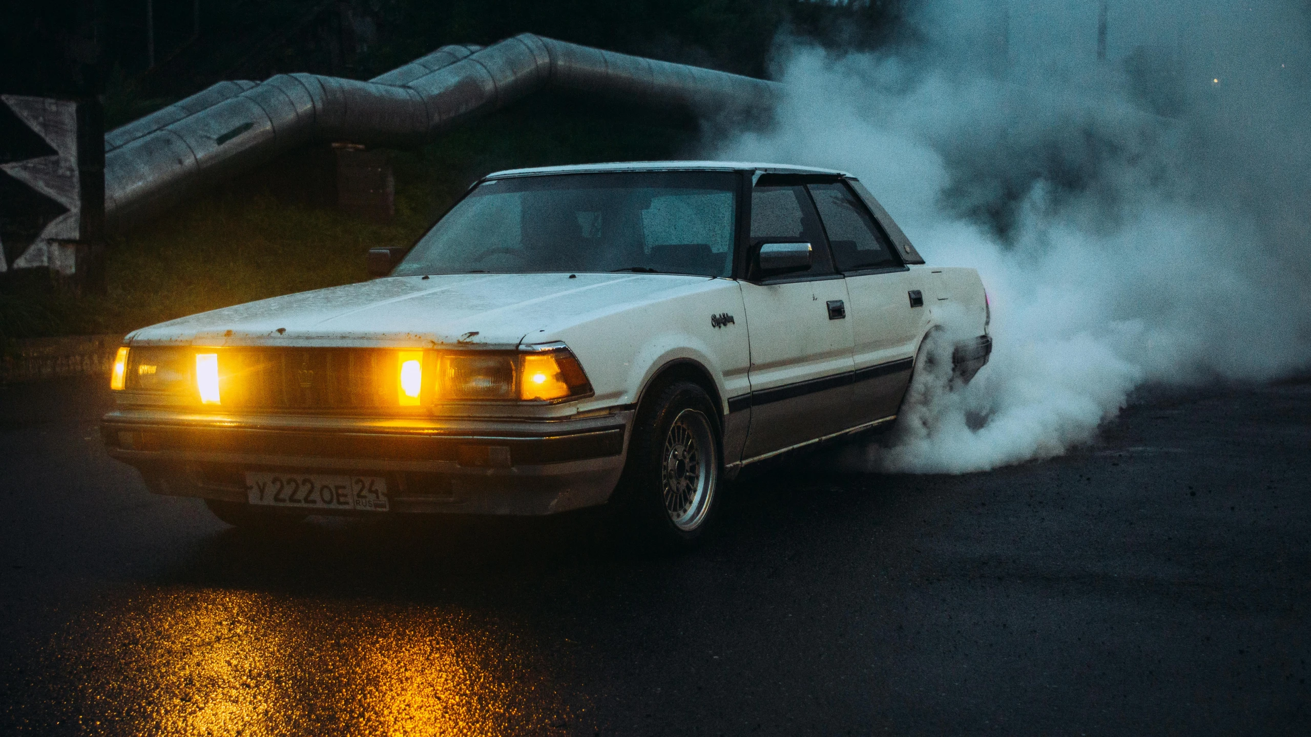 a car burns as smoke rises behind it on a city street