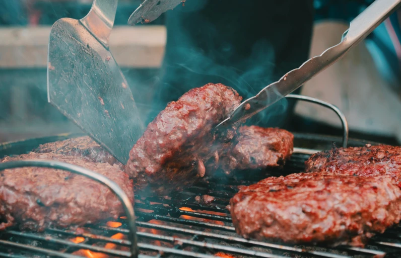 some hamburger patties cooking on the grill, while being grilled