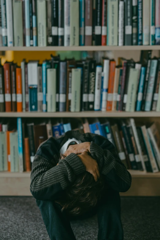 a man sitting down on the ground in front of books