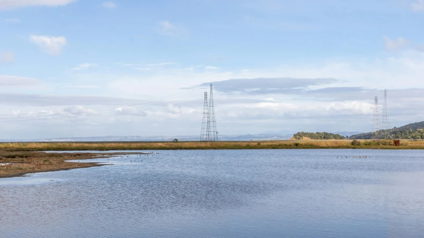 a large body of water with telephone towers in the background