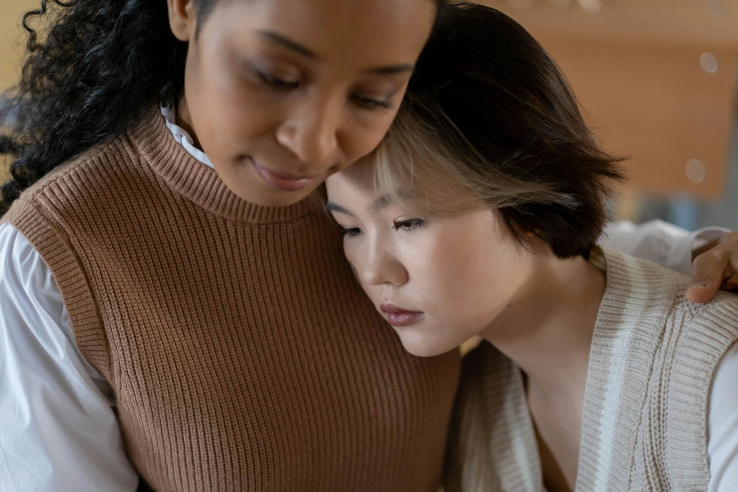 two women using a cell phone together with their arms around each other