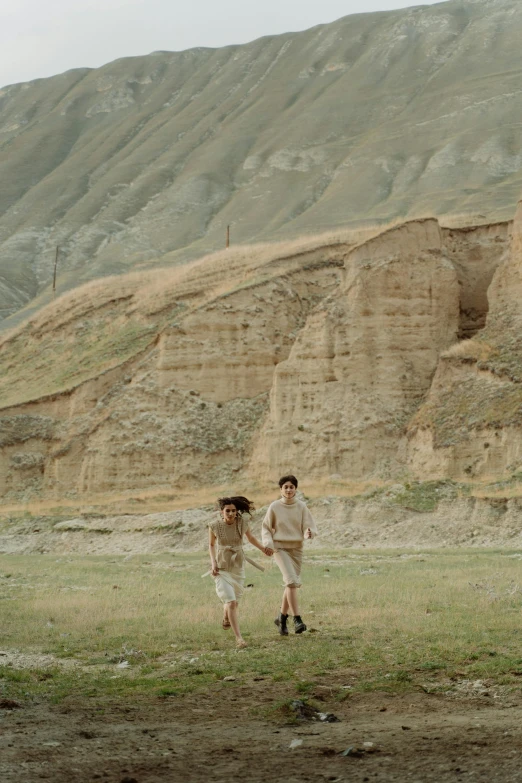 a couple walking in the grass with a mountain in the background