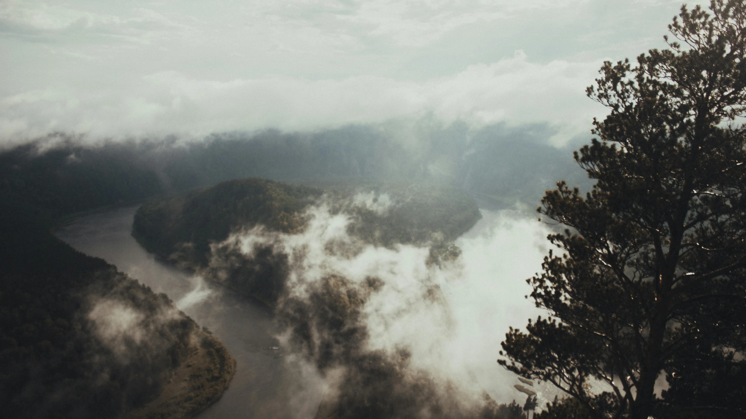 a view from a height hill overlooking a river running through a mountain