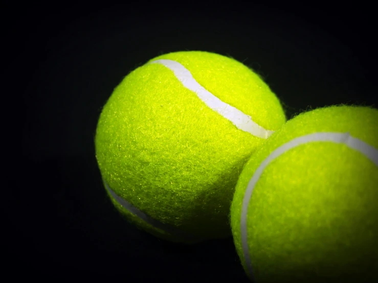 three tennis balls on a dark surface