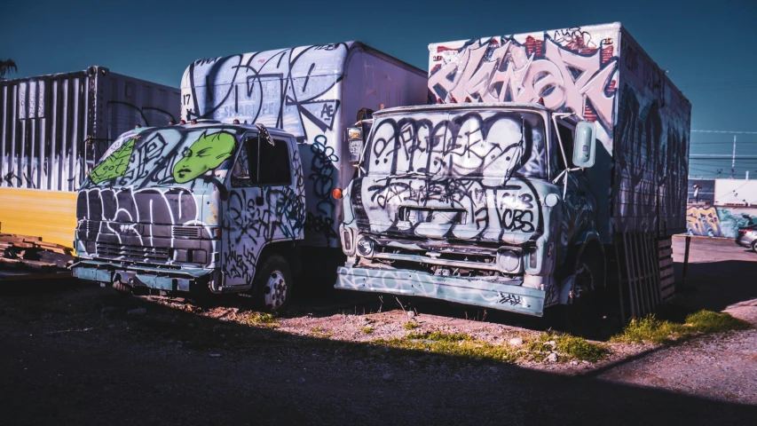 two trailers covered in graffiti on the side of a road