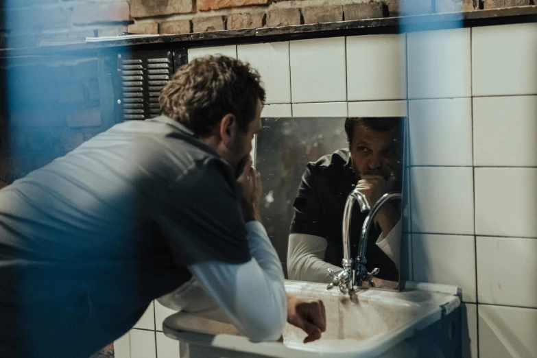 a man squatting down in front of a sink