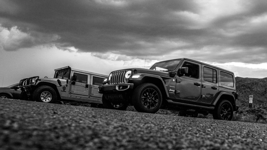 a jeep parked in a large field with dark clouds