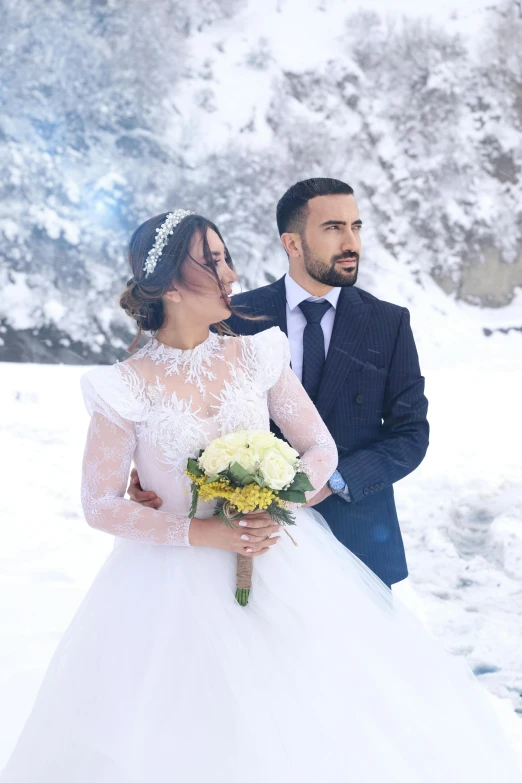 the bride and groom are standing in the snow