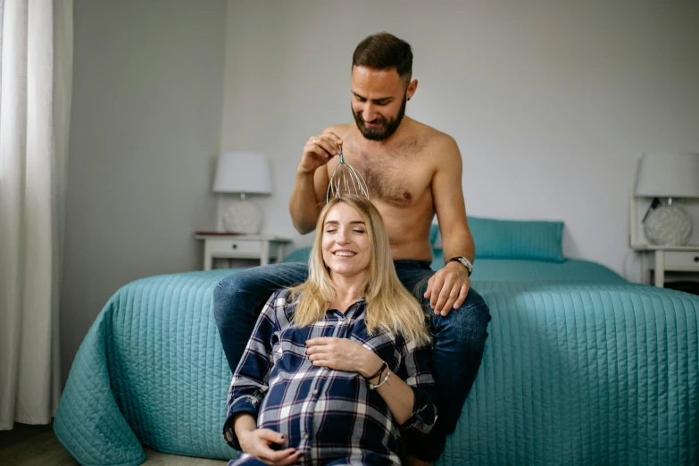 the couple is having their hair brushed while sitting on a bed