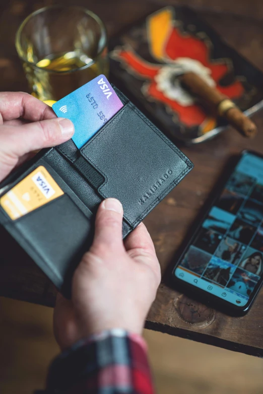 someone is putting money into the pocket of a leather wallet