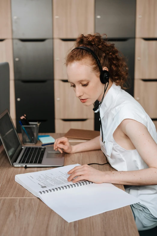 woman in headset at desk with notebook and laptop