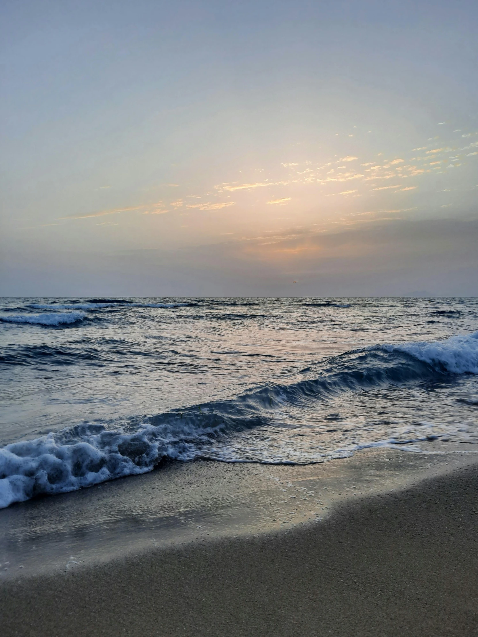 a beach with a water line and ocean waves