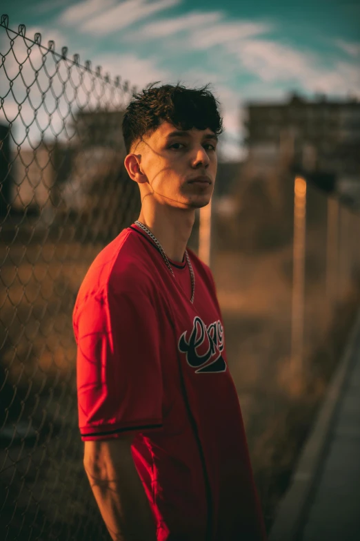 a man in red is standing next to a chain link fence