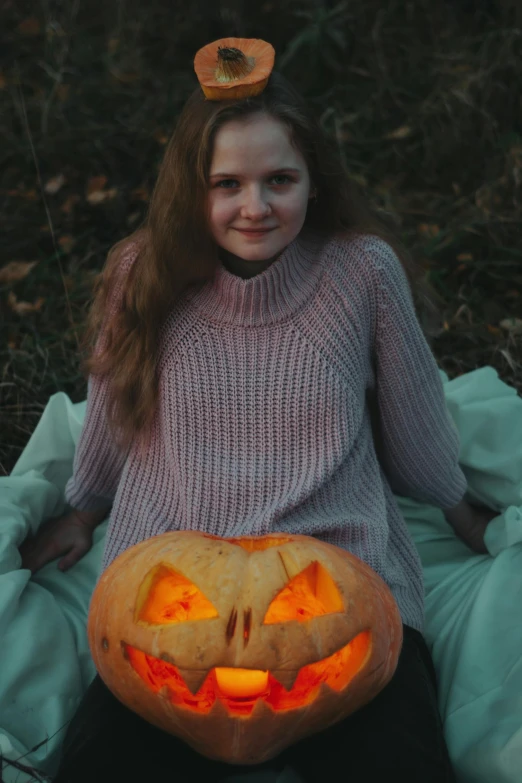 a girl holding a jack - o'lantern on the grass