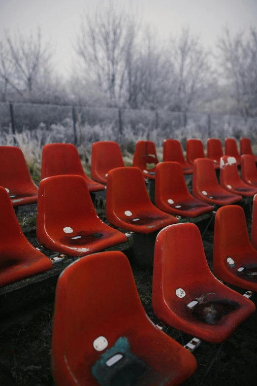 an empty stadium bench has been decorated with red plastic seats