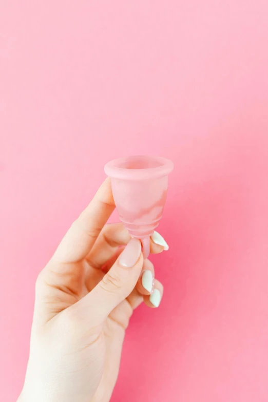 hand holding an empty s glass on a pink background