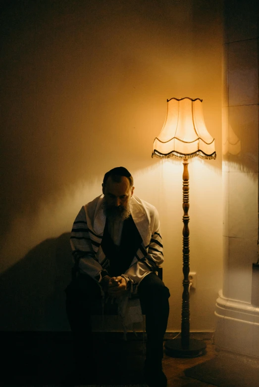 a man is sitting by a lamp on the floor