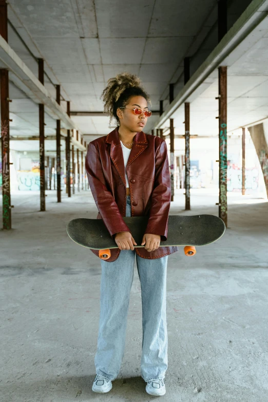 a girl holding a skateboard is posing for the camera