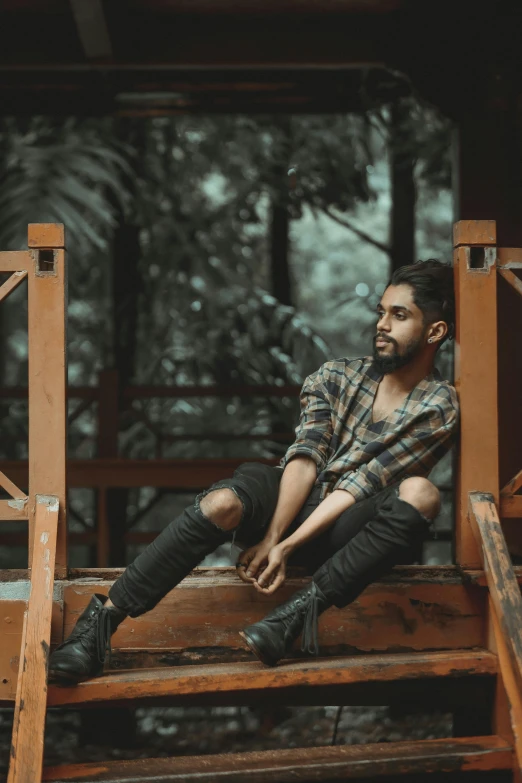 a man in black pants and plaid shirt sitting on a bench