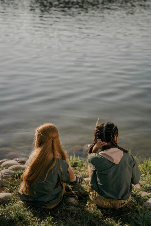 two people are on the grass by the water